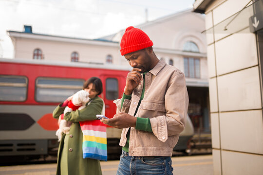Man Using Phone While Woman Holds Dog at Train Station