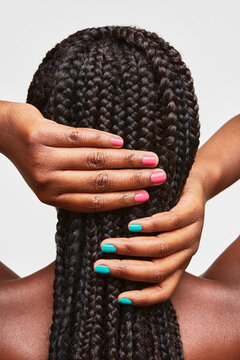 Person caring for long braided hair with colorful nails