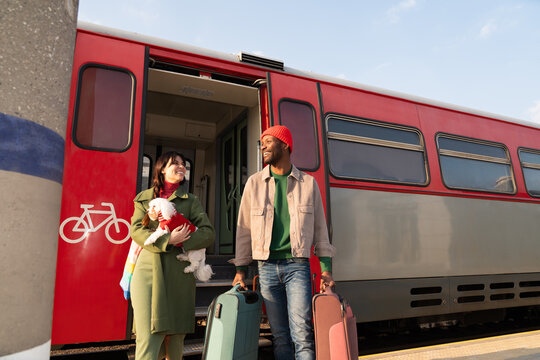 Couple Arrives at Train Station With Luggage and Dog in Hand