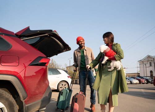 Travelers Loading Luggage Into Car With a Dog in the Parking Lot