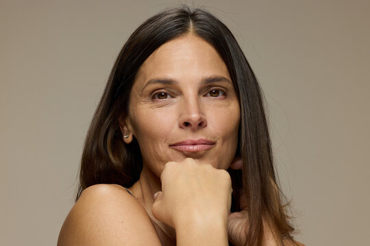 Woman Smiling and Posing With Hands on Chin in Simple Backdrop