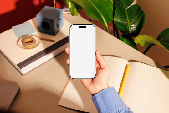 Phone mockup with white screen in office workspace