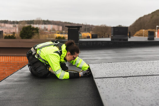 Technician Inspecting Solar Panel Edges on Flat Roof