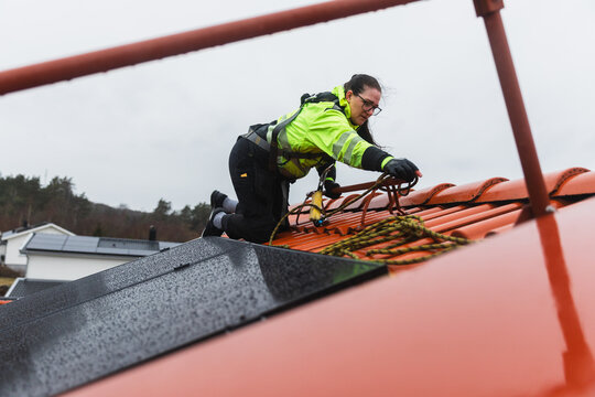 Technician Securing Fall Protection on Red Tile Roof