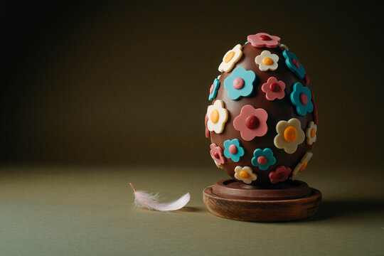 a chocolate easter egg with flowers beside a pink feather