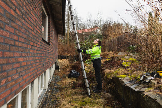 Specialist Using Telescopic Ladder for Residential Roof