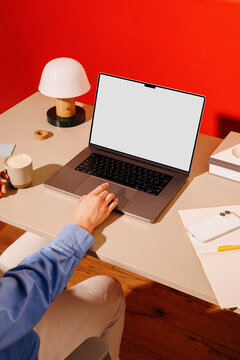 Hand using laptop mockup on office desk with coffee