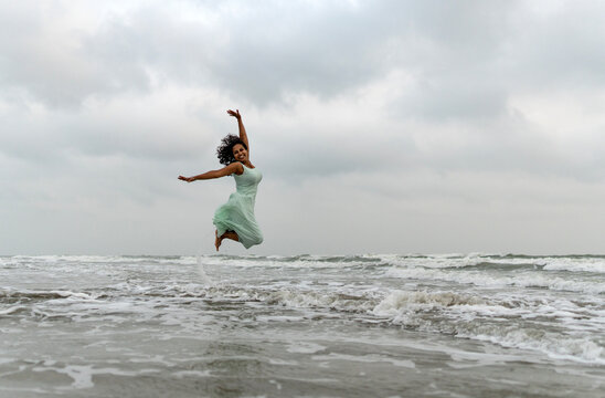 Indian woman jumping and enjoying beach time  