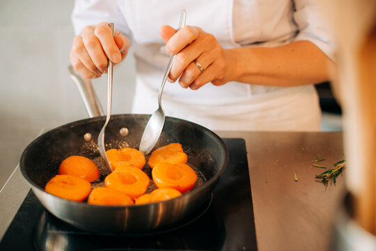 Chef turning apricots in pan during cooking process