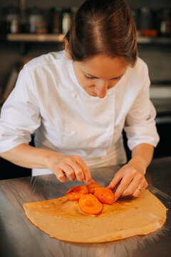 Chef arranging caramelized apricots on crepe for dessert prepara