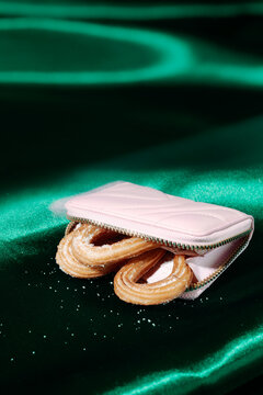 a pink purse partly open with churros on green satin