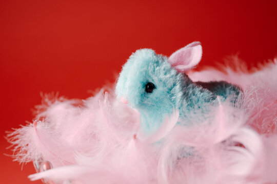 a fluffy blue easter bunny in a nest of pink feathers