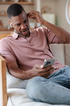 Man looking at phone with a confused expression.