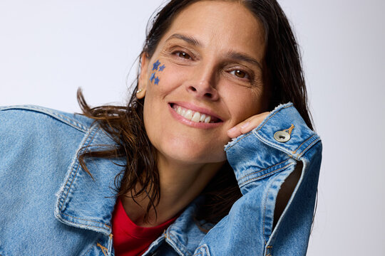 Woman With Blue Stars on Face Smiles in Denim Jacket