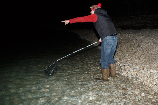 Man with a landing net on a night fishing trip