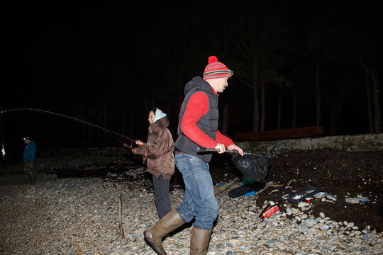 Man and woman catch fish at night