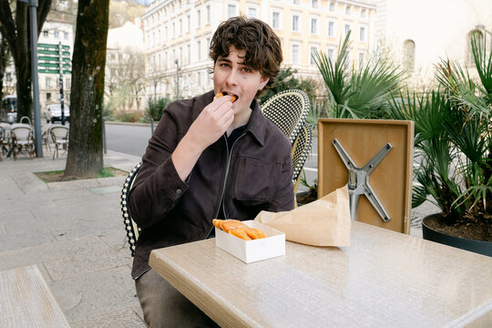 young man eating croissant and bugne in Lyon France