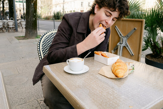 young man eating croissant and bugne in Lyon France