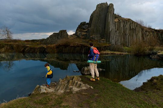 Father and child exploring basalt lake landscape