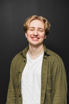 Smiling young man in an olive shirt on a black background