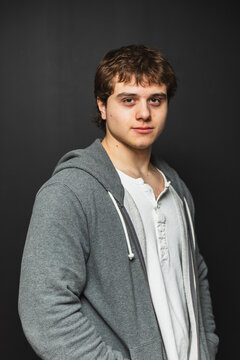 Confident student in a grey hoodie on a black background