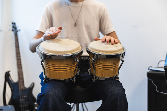 Student playing bongos in a bright rehearsal studio