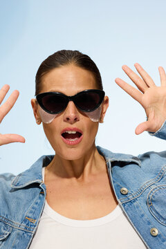 Woman Shows Surprise With Hands Raised While Wearing Sunglasses