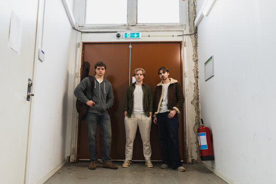 Young music band posing in a hallway with a guitar case