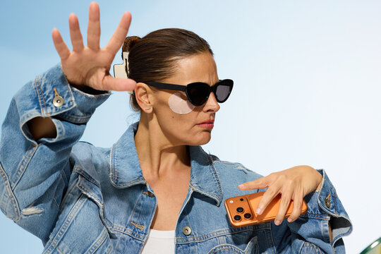 Woman Posing With a Phone and Sunglasses in a Bright Setting