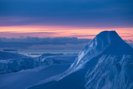 Iceberg peak in Greenland on a sunset backdrop