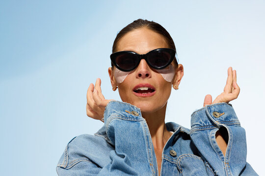 Woman With Sunglasses and Face Masks Poses in Bright Sky Background
