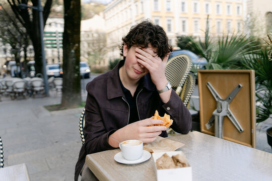 young man eating croissant and bugne in Lyon France