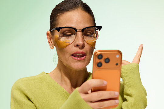 Woman Uses Smartphone While Wearing Eye Patches for Skincare