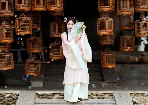 Woman in ancient costume against the backdrop of a birdcage