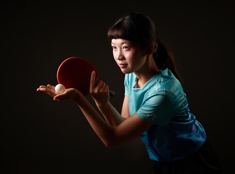 Chinese woman in sportswear is holding a ping-pong paddle and ball