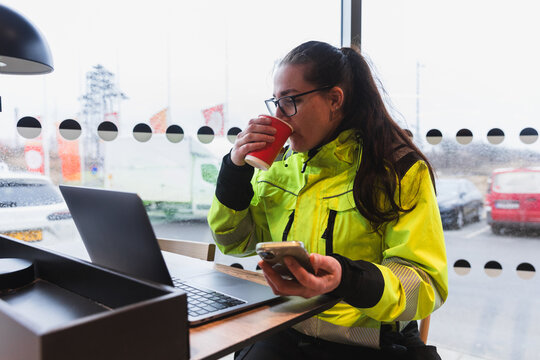 Female Technician Drinking Coffee While Managing Schedules