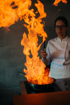 Dramatic flamb&Atilde;&copy; cooking with flames rising from frying pan