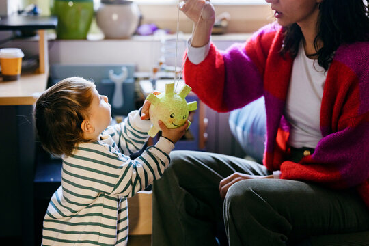 Mother Playing With Toddler Holding a Toy