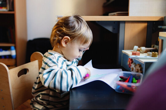 Toddler Drawing at Table With Crayons in Playroom