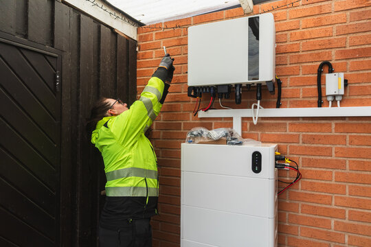 Female Technician Inspecting Solar Inverter Wiring and Connections
