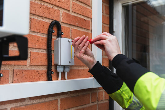 Technician Checking Junction Box on Brick Wall