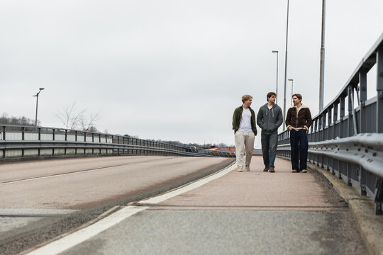 Trio of male friends walking on a bridge pathway