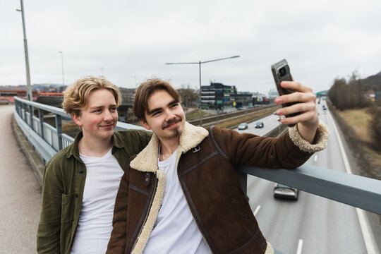 Two male friends taking a selfie on an urban bridge.