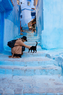 A woman caressing a cat in Chefchaouen's old town