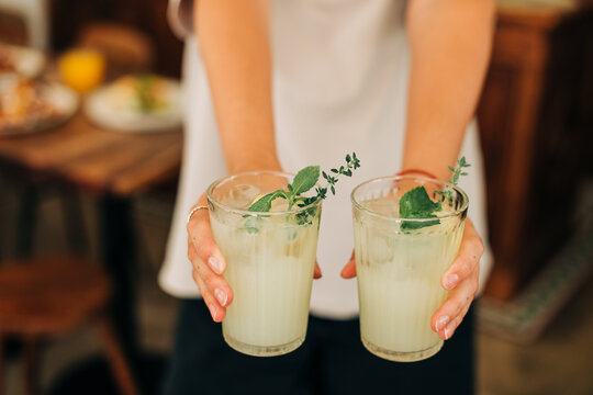 Closeup of female hands holding fresh drinks with mint and lemon