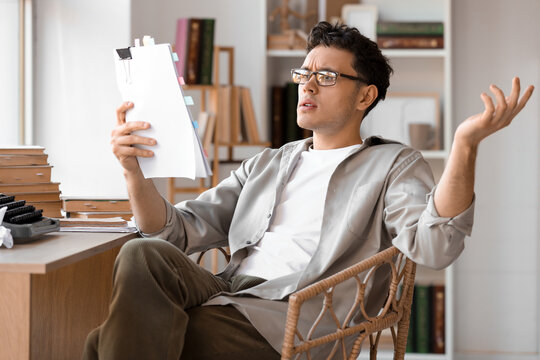 Male screenwriter reading script at table in office