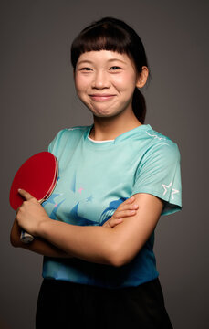 Chinese woman in sportswear is holding a ping-pong paddle and ball
