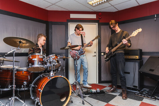 Indie Rock Trio Rehearsing Together in Recording Studio