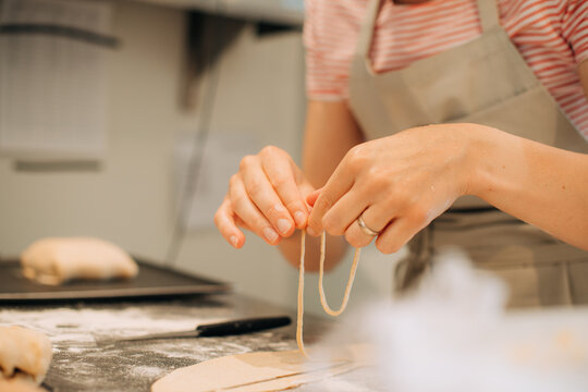 Female hands shaping dough decorations in kitchen