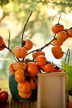 Closeup of a vase decorated with ripe persimmons